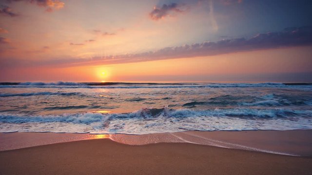 Tropical beach sunrise. Ocean waves splashing on the sand