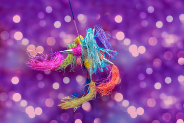 mexican piñata party hanging on purple and  red background with multi-colored glitters celebrating...