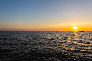 Sunset at Tonle Sap Lake, Cambodia, near the Kampong Phluk Floating Village and Siem Reap. Tourism boats cruising on the water to enjoy the breathtaking colorful sunset. Sunset horizon over the sea.