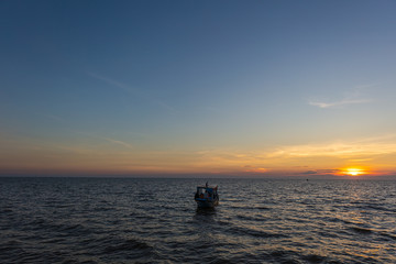 Naklejka na ściany i meble Sunset at Tonle Sap Lake, Cambodia, near the Kampong Phluk Floating Village and Siem Reap. Tourism boats cruising on the water to enjoy the breathtaking colorful sunset. Sunset horizon over the sea.