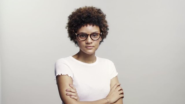 Smiling young woman wearing eyeglasses on white background. Happy female with curly hair looking at camera.