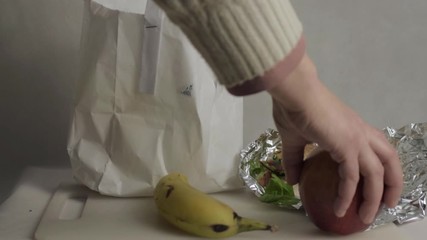 Packing a healthy lunch with sandwich and orange juice into a bag medium shot - Powered by Adobe