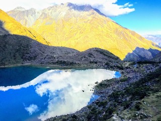A view of clouds reflecting on a lake high up in the andes mountains as the sun sets