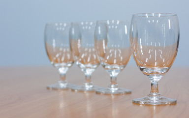 Wine glasses lined up on a brown wooden table.