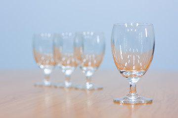 Wine glasses lined up on a brown wooden table.