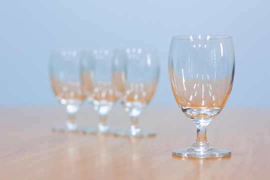 Wine Glasses Lined Up On A Brown Wooden Table.