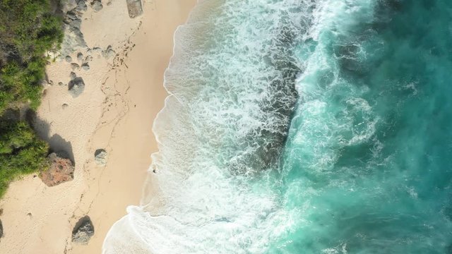 View from above, stunning aerial view of a rocky shore with a beautiful beach bathed by a rough sea during sunset, Nyang Nyang Beach (Pantai Nyang Nyang), South Bali, Indonesia.