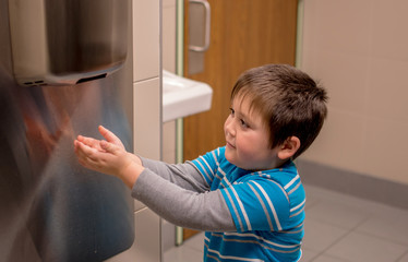 boy drying hands with blow dryer