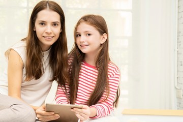 Mom and daughter using computer for social media and entertaining it living room.On line education for young student at home