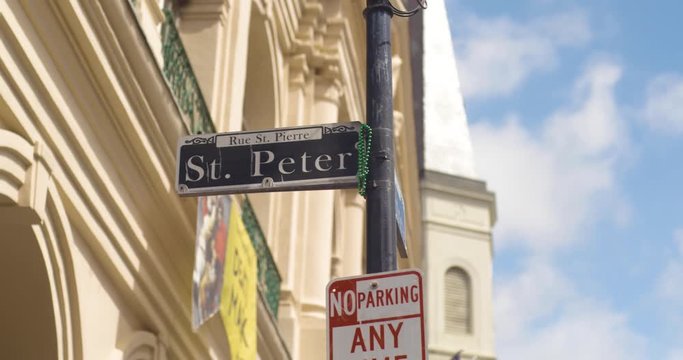 St Peter Street New Orleans Street sign at the corner with NOLA Decor in the background as they move in slow motion.