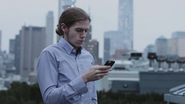 Adult Male on mobile phone on rooftop in Manhattan New York