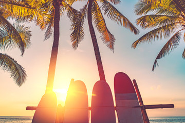 Surfboard and palm tree on beach background.