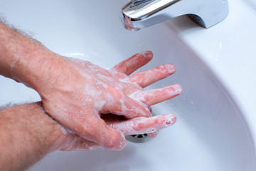 Fototapeta premium A Man is washing his hands with soap in bathroom.