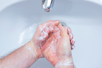 A Man is washing his hands with soap in bathroom.