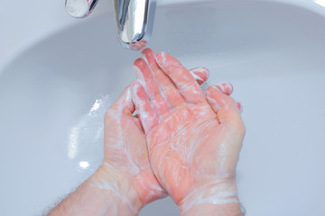 Fototapeta premium A Man is washing his hands with soap in bathroom.