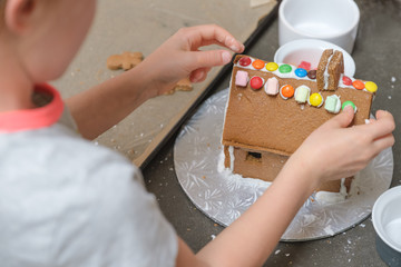 girl putting finishing touches to gingerbread house