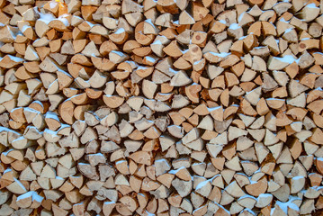 Harvesting firewood for the winter. Chipped wood fire is covered with snow outdoors. Wood for the fireplace. Stacked dry chopped firewood.