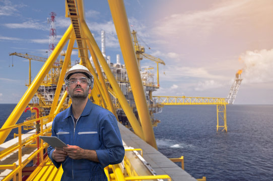 Caucasian man engineer staff worker with tablet in hand and offshore rig background concept.