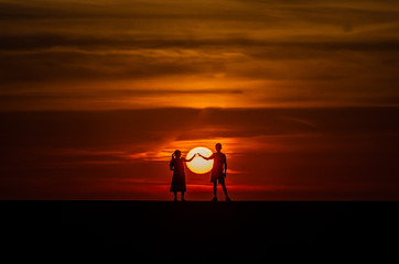 silhouette of man sitting on the beach at sunset