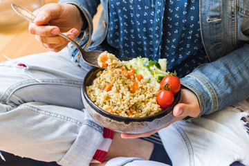 Vegetable bulgur pilaf or pulao. Woman holds in hands on legs turkish  or Levantine Arabic durum wheat cooked grain as part of vegan, vegetarian healthy  diet food.