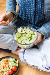 Vegan detox salad with green vegetables in bowl. Vegetarian cabbage and cucumber salad. Healthy diet food in hands on legs