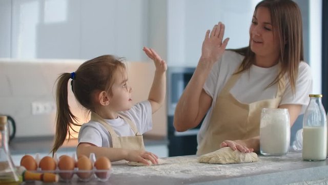 Mom and daughter finished cooking in the kitchen and give five onions. Beat off five. A clap on the hands. Cooking together in the kitchen, successfully educating daughter