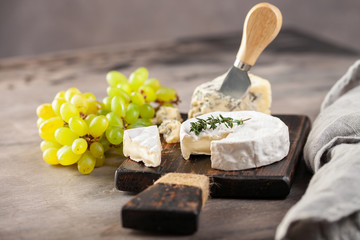 Cheese Brie and Dorblu or Gorgonzola on a board with grapes and olives. Italian food antipasti