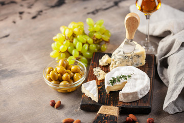 Cheese Brie and Dorblu or Gorgonzola on a board with grapes and olives. Italian food antipasti