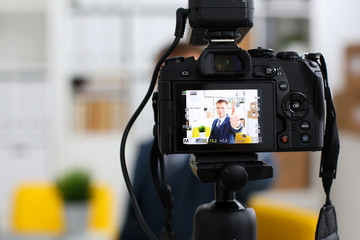 Male in suit and tie show confirm sign arm making promo videoblog or photo session in office camcorder to tripod closeup. Vlogger promotion selfie solution or finance advisor management information © H_Ko
