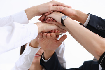 Group of people in suits crossed hands in pile for win closeup. White collar leadership high five cooperation initiative achievement corporate life style friendship deal heap stack concept
