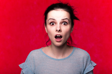 beautiful emotional girl in a blue t-shirt on a red background