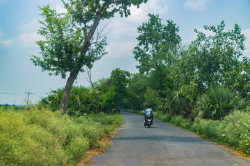 A Motorcycle carrying 2 passengers in an empty road