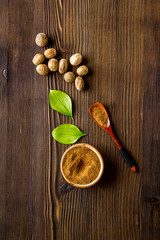 Nutmeg - ground indian condiment in spoon - on wooden background top-down