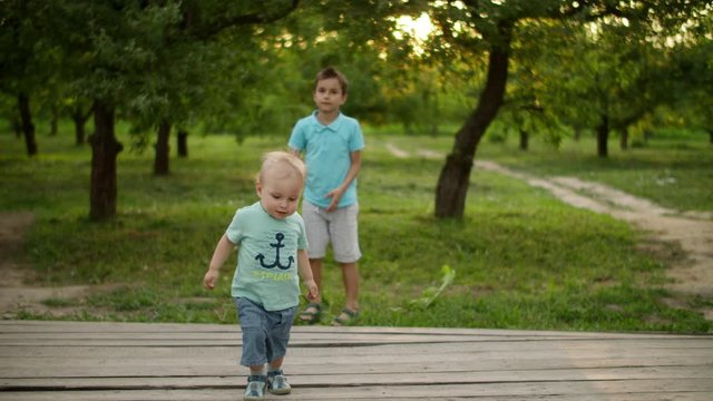 Cute brothers playing in summer park. Smiling siblings spending time together