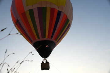 Fototapeta premium A balloon with a large wicker basket and passengers rises into the sky
