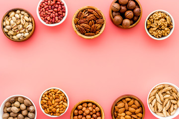 Nuts set in bowls on pink background top-down frame copy space mockup
