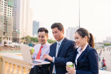 Fototapeta premium Asian business woman and men working outside on computer
