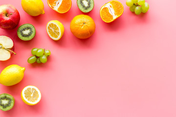 Oranges, lemon, apple, kiwi and grape - healthy food concept with fruits - on pink background top-down frame copy space