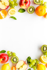 Oranges, lemon, apple, kiwi and grape - healthy food concept with fruits - on white background top-down frame copy space