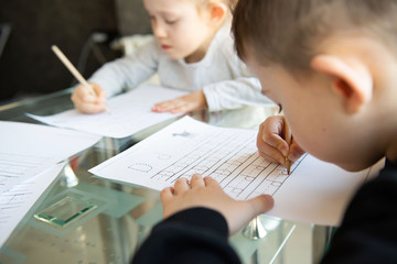 Schoolboy and schoolgirl writing letters. Close-up  pencil in the hand of child. Children learning...