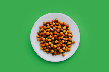 the banner of healthy eating. ready fried chickpeas on a white plate on a clean green background.