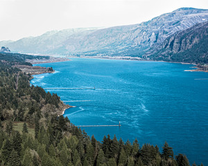 Fototapeta na wymiar Columbia River in its full Blue glory with mountains and evergreen tree in the background