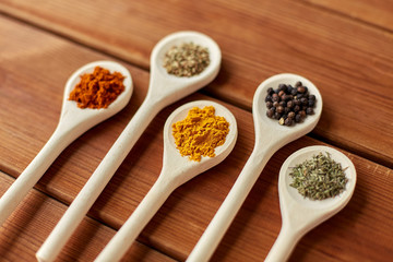 food, culinary and unhealthy eating concept - spoons with different spices on wooden table