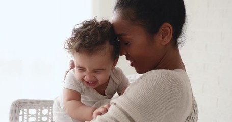 Funny adorable healthy african american baby girl or boy playing with mom at home. Young loving mother hugging taking care of little infant child daughter, cuddling, enjoying sweet motherhood concept. - Powered by Adobe