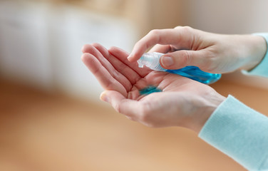 hygiene, health care and safety concept - close up of woman spraying antibacterial hand sanitizer