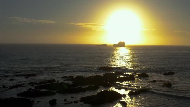 Aerial drone push in shot of the sunset falling between the rocks in the ocean at San Simeon California USA