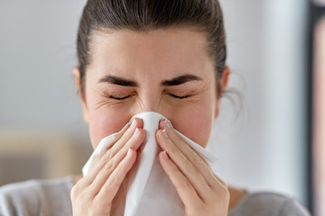 healthcare, cold, allergy and people concept - close up of sick woman blowing her runny nose in...
