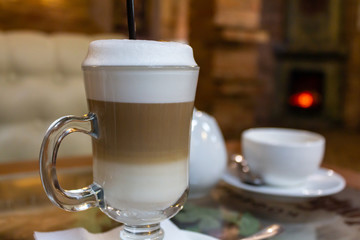 Latte macchiato in a glass cup with a straw on the table