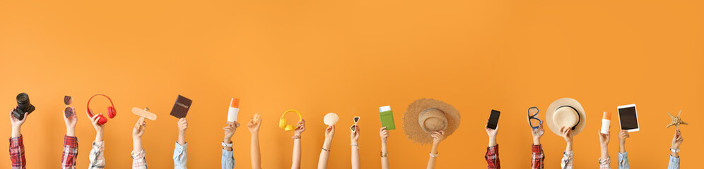 Many hands with travel items on color background