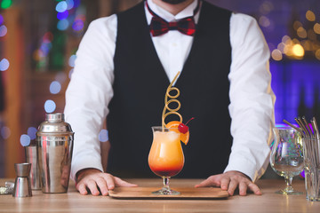 Male bartender with tasty cocktail in pub